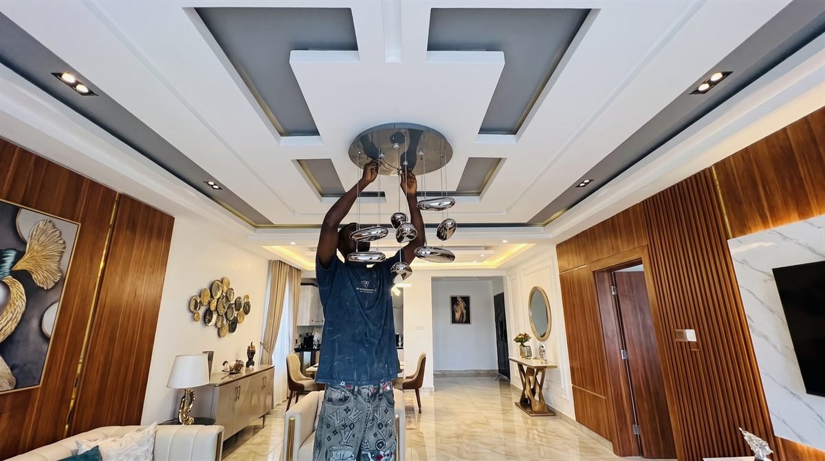 Technician installing decorative pendant lighting in a luxury Accra residence