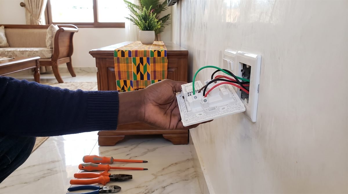 Electrician installing a wall switch and socket in a residential living room